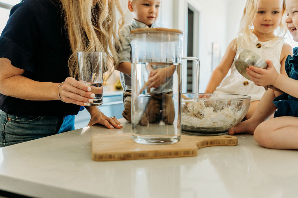 Family gathered around a pitcher of water in the kitchen